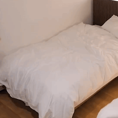 A Woman In A Black Jacket Is Making A Bed . GIF