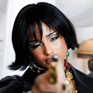 A Woman In A Black Jacket Is Pointing A Gun GIF