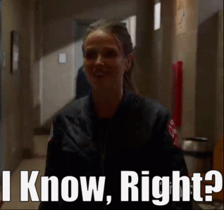 A Woman In A Black Jacket Is Standing In A Hallway And Says I Know Right . GIF