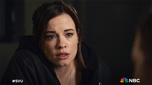 A Woman In A Black Jacket With The Nbc Logo Behind Her GIF