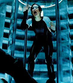 A Woman In A Black Jumpsuit Is Screaming In A Glass Elevator GIF