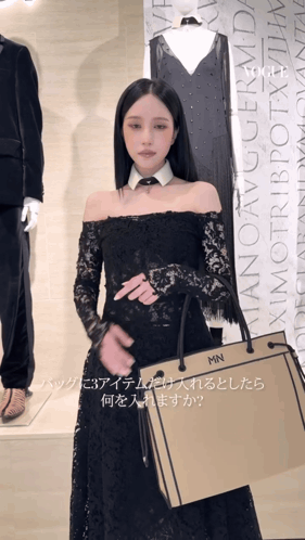 a woman in a black lace dress is holding a bag that says mn on it