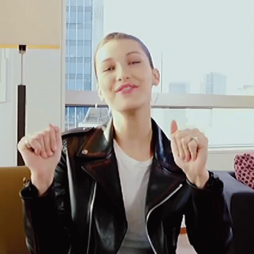 A Woman In A Black Leather Jacket Is Giving A Thumbs Up Sign GIF