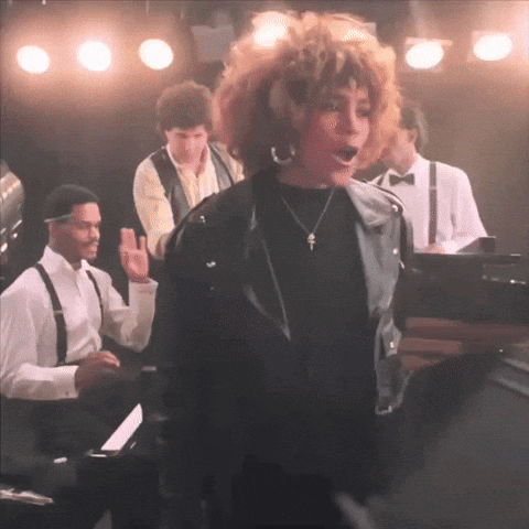 a woman in a black leather jacket is singing on stage