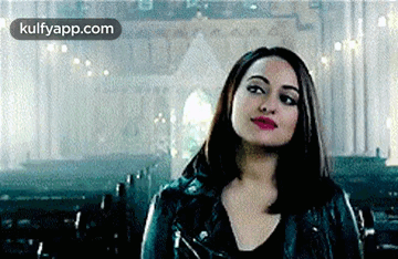 A Woman In A Black Leather Jacket Is Standing In A Church . GIF