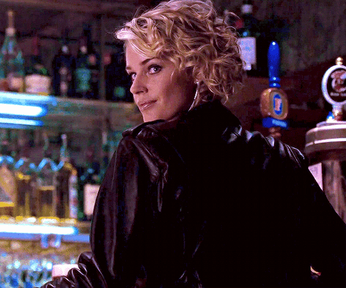 A Woman In A Black Leather Jacket Stands In Front Of A Beer Tap That Says Budweiser GIF