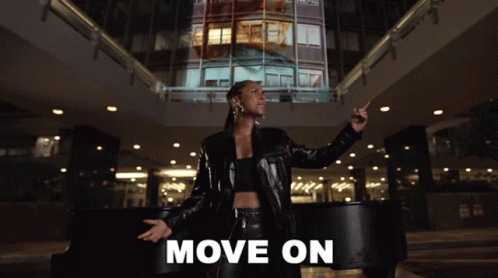 A Woman In A Black Leather Jacket Stands In Front Of A Piano With The Words Move On Written Below Her GIF