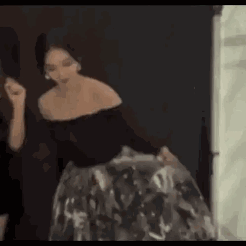 a woman in a black off the shoulder dress is standing next to another woman .