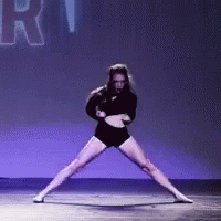 a woman in a black outfit is dancing on a stage with the word rhythm in the background .