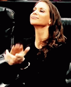 A Woman In A Black Shirt Is Clapping Her Hands In The Air GIF
