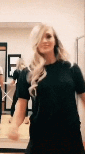A Woman In A Black Shirt Is Dancing In A Room . GIF