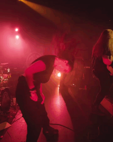 A Woman In A Black Shirt Is Dancing On Stage GIF