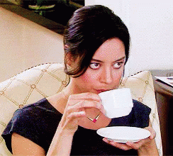 A Woman In A Black Shirt Is Drinking From A White Cup GIF