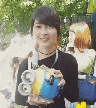a woman in a black shirt is holding a blue and yellow object with the number 80 on it