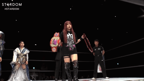 A Woman In A Black Shirt Is Holding A Wrestling Belt With The Word Stardom On It GIF