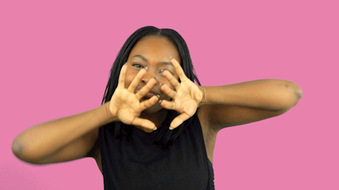 A Woman In A Black Shirt Is Making A Face With Her Hands GIF