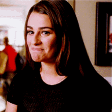 A Woman In A Black Shirt Is Making A Funny Face And Looking At The Camera . GIF
