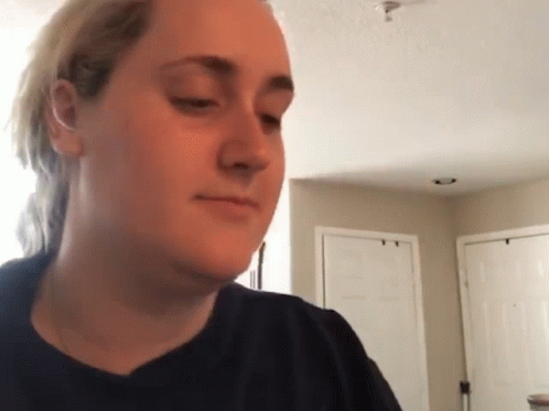 A Woman In A Black Shirt Is Making A Funny Face In A Living Room . GIF