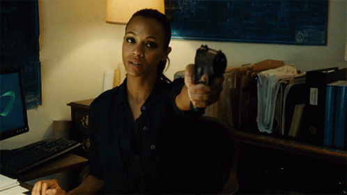 A Woman In A Black Shirt Is Pointing A Gun At Someone GIF