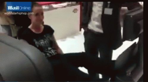 A Woman In A Black Shirt Is Sitting In The Back Seat Of A Car In Front Of A Blue Sign That Says Mail Online GIF