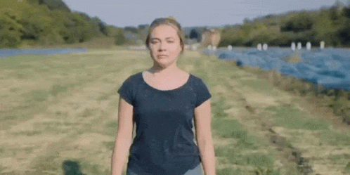 A Woman In A Black Shirt Is Standing In A Field . GIF