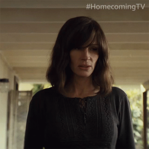 A Woman In A Black Shirt Is Standing In A Hallway With #Homecoming Tv Written Above Her GIF