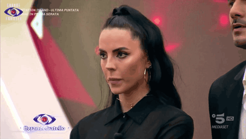 A Woman In A Black Shirt Stands In Front Of A Sign That Says 5 Hd GIF