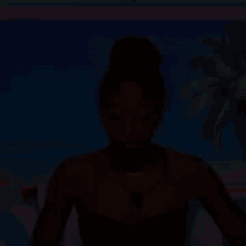 a woman in a black strapless top and necklace is sitting in front of a beach scene .