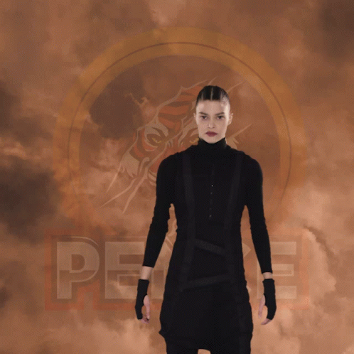 A Woman In A Black Suit Is Doing A Split With The Word Peace Behind Her GIF
