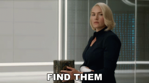 A Woman In A Black Suit Is Holding A Box With The Words Find Them Below Her GIF