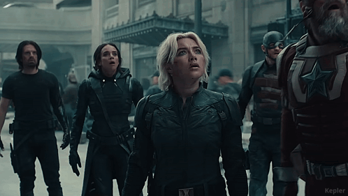 Woman In Black Suit With X On Chest In Front Of Soldiers GIF