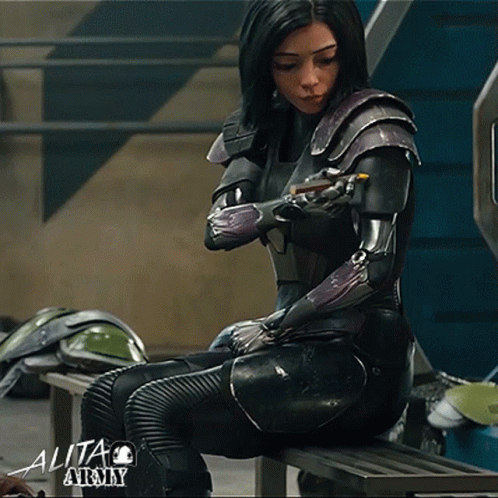 A Woman In A Black Suit With The Number 9 On Her Arm Sits On A Bench GIF