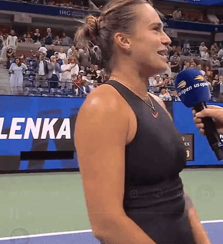 a woman in a black tank top is being interviewed by a man with a microphone that says us open on it