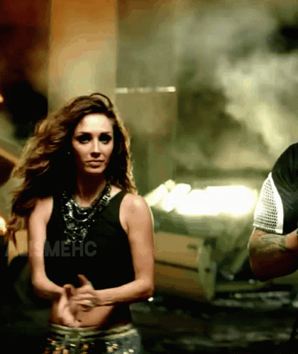 A Woman In A Black Tank Top Is Dancing Next To A Man In A Black Shirt With The Word Mehc On It GIF