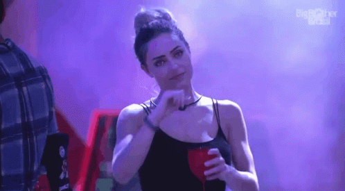 a woman in a black tank top is holding a red drink and making a face .