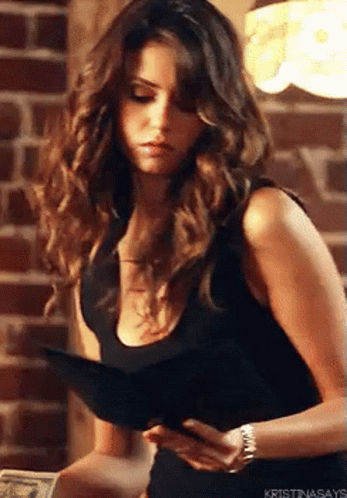 A Woman In A Black Tank Top Is Holding A Wallet And A Book . GIF