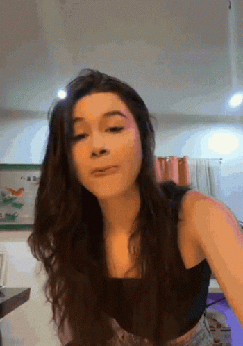 A Woman In A Black Tank Top Is Making A Face GIF