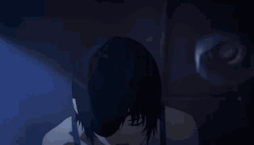 A Woman In A Black Tank Top Is Pointing Up With Her Fingers . GIF