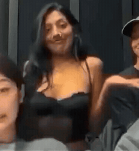 A Woman In A Black Tank Top Is Sitting Next To A Man In A Hat . GIF