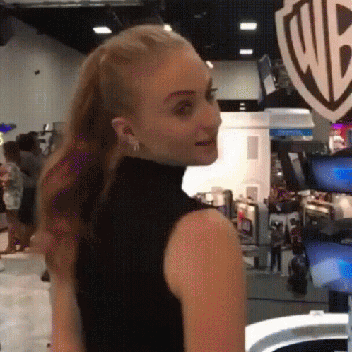 A Woman In A Black Tank Top Is Standing In Front Of A Wb Logo GIF