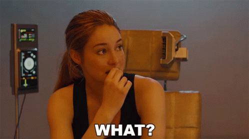 A Woman In A Black Tank Top With The Word What On Her Chest GIF