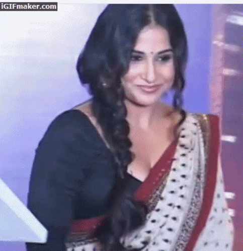 A Woman In A Black Top And A White And Red Polka Dot Saree Is Smiling GIF