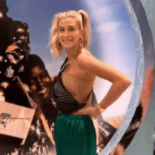 A Woman In A Black Top And Green Pants Is Standing Next To A Woman In A Black Top And Green Pants . GIF