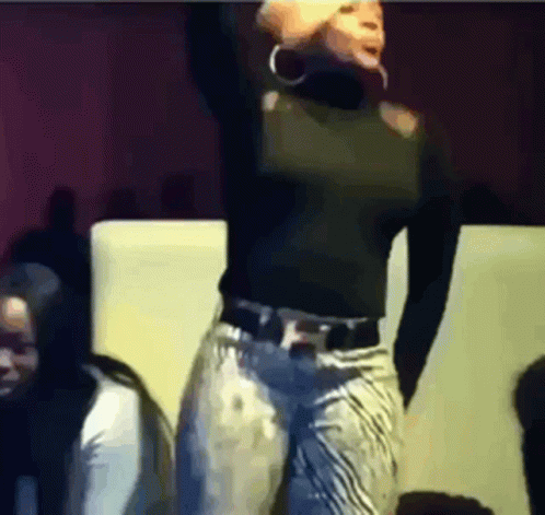 A Woman In A Black Top And Jeans Is Dancing GIF