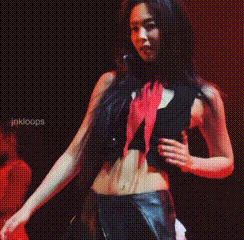 A Woman In A Black Top And Red Scarf Is Standing In Front Of A Sign That Says Jakloops GIF