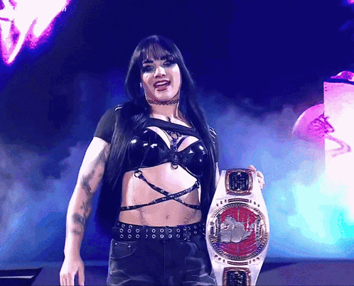 A Woman In A Black Top Is Holding A Belt That Says ' World Heavyweight Champion ' On It GIF
