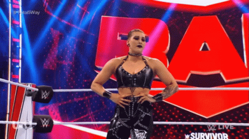 A Woman In A Black Top Is Standing In A Wrestling Ring . GIF