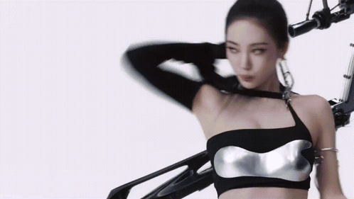 A Woman In A Black Top Is Standing Next To A Robot Arm . GIF