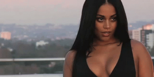 A Woman In A Black Top Is Standing On A Balcony Overlooking The City . GIF