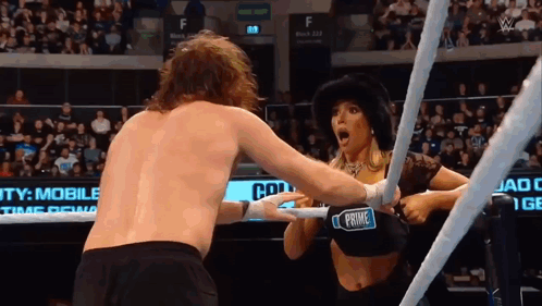 A Woman In A Black Top With The Word Prime On It Is Wrestling A Man In A Ring GIF